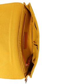 Gul canvashandväska med rymligt inre, utrustad med en dragkedjeficka och läderdetaljer. Strukturerad tyg och enkel design.