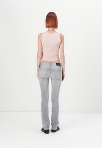 Lys rosa ribbet crop top kombinert med tettsittende lys grå jeans. Jeansene har baklommer og en svart etikett i livet.