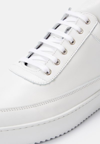 White leather sneaker with flat white laces. Features silver eyelets and a textured rubber sole. Smooth finish with subtle stitching details.