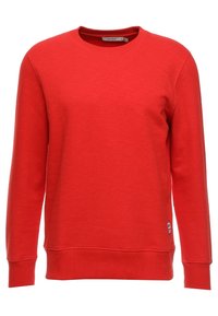 Sudadera de cuello redondo de manga larga en rojo con puños y dobladillo acanalados, pequeña etiqueta blanca de la marca cerca del dobladillo en el lado izquierdo.