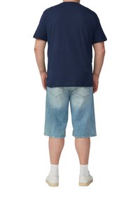 Granatowa koszulka bawełniana, krótki rękaw, w połączeniu z jasnoniebieskimi szortami dżinsowymi o wyblakłym efekcie oraz białymi skarpetkami z beżowymi trampkami.