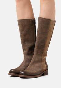 Botas altas de ante marrón con cremallera lateral, paneles más claros en contraste, puntera redondeada y tacón bajo apilado de madera.