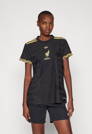 Zwarte sporttrui met een ronde hals, korte mouwen, textuurpatronen, gouden accenten en het "MÉXICO" logo. Gepaard met zwarte shorts.