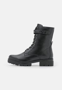 Bottes de cheville en cuir noir avec un bout rond, design à lacets, sangle réglable et semelle �à crampons épaisse. Texture lisse avec des coutures subtiles.