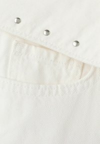 Tissu en denim blanc avec une poche et trois rivets métalliques argentés le long d'un bord plié.
