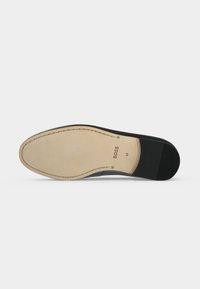 Semelle de chaussure habillée en cuir beige et noir avec des détails de couture, marquage BOSS et taille 41 sur la zone du talon.
