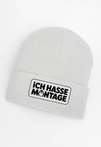 Gray knitted beanie featuring a black patch with the text "¡ICH HASSE MONTAGE!" and a cartoon penguin, with a ribbed design for texture.