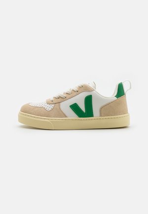 Sneakers met een beige suède en witte leren bovenwerk, met een groen logo. Ronde neus, platte zool en geperforeerde details.