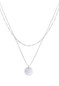 Collier double couche en argent avec un pendentif circulaire texturé, une chaîne plate et l'autre torsadée, affichant des longueurs et des designs variés.