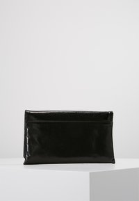 Pochette en cuir noir avec une forme rectangulaire élégante, une texture brillante et un design simple. Présente une poche zippée discrète à l'arrière.