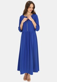 Niebieska maxi sukienka z lekkiego materiału, okrągłym dekoltem, rękawami o długości trzech ćwierć oraz zamkiem błyskawicznym z przodu. Rozkloszowany dół ze szczegółami marszczenia.