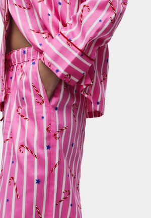 Pink pajama set with white stripes and candy cane patterns. Features blue stars, a relaxed fit, and an elastic waistband with pockets.