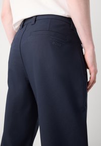 Ναυτικά μπλε παντελόνια από λείο ύφασμα, διαθέτοντας μια πίσω τσέπη με διακριτό ανάγλυφο λογότυπο "Porsche BOSS" και εφαρμογή που ταίριαζει.