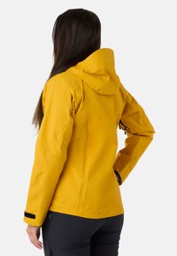 Vandtæt gul jakke med hætte, der har lange ærmer og sorte velcro-detajler. Glat, let materiale med en tætsiddende design.