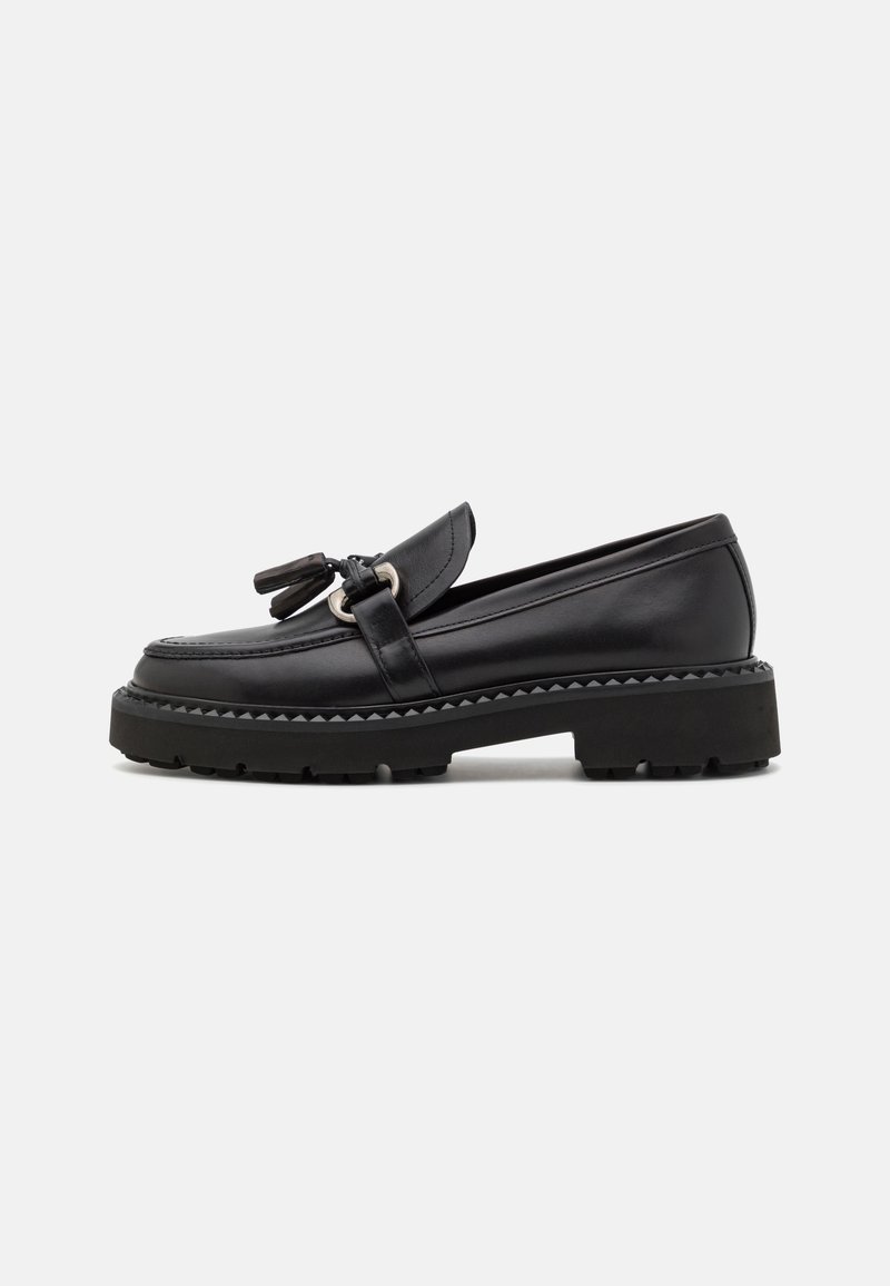 Mocassins en cuir noir avec des accents de pampilles, semelle en caoutchouc épaisse et détails en bord texturé, affichant un design élégant et un bout arrondi.