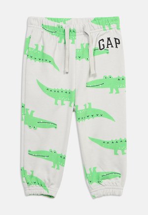 Bijele dječje hlače s uzorkom zelenih krokodila, elastični pojas sa špagom za vezanje, elastični rubovi na nogavicama i logo "GAP" na prednjoj desnoj strani.