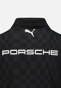 Czarna koszulka polo w wzór w kratkę, z białym logo "Porsche" oraz białym logo Puma na tylnej części kołnierza.