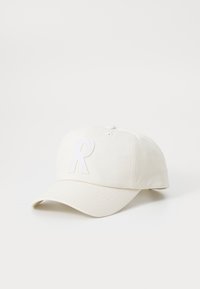 White cotton baseball cap with a curved brim, featuring a textured white "R" logo on the front and ventilation eyelets.