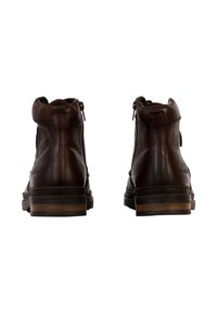 Bottines en cuir marron avec fermeture éclair, pied rond et talon en bois empilé. Présente des détails de couture sur la tige.