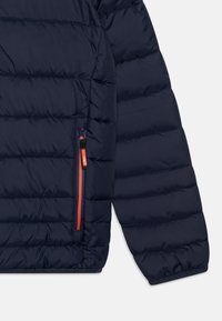 Námořnická péřová bunda s prošívaným designem, která má boční kapsu na zip s oranžovým zipem a značkováním na táhle. Hladká textura.
