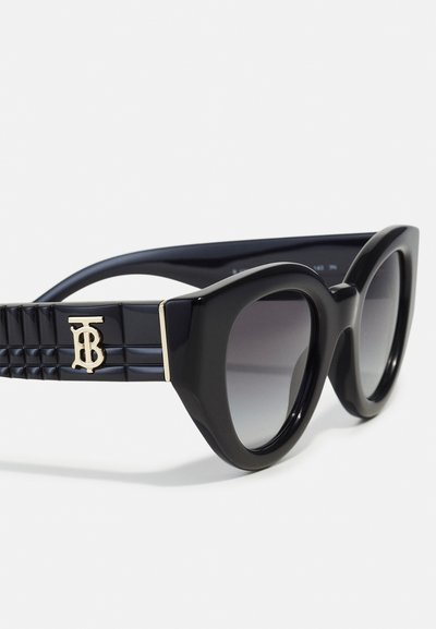 Svarta solglasögon med en kraftig båge, gradientlinser och texturerade svarta glasögonbågar med en guldfärgad logotyp som accent.