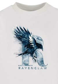 Valge T-särk, millel on sinine ja must varesemuster, mis on ühendatud tähisega "R" ja tekstiga "RAVENCLAW", näidates akvarelliefekti.