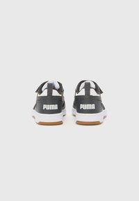 Baskets noires avec le logo PUMA blanc, présentant un design à deux bandes Velcro et une semelle intermédiaire blanche avec une semelle extérieure en caoutchouc naturel.