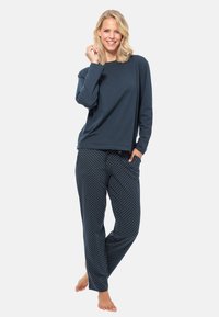 Marinblå långärmad topp kombinerad med pyjamasbyxor i prickar, med resårmidja. Mjuk tyg med avslappnad passform.