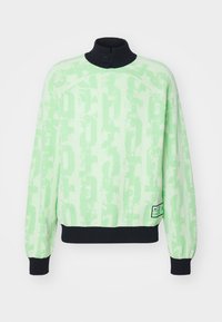 Maglione verde chiaro con motivo astratto, colletto nero con bottone, polsini e vita nera, e piccolo logo ricamato vicino all'orlo.