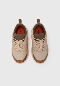Μπεζ αθλητικά παπούτσια με υφασμάτινο επάνω μέρος με υφή, καφέ λεπτομέρειες και πορτοκαλί εσωτερικό. Διαθέτουν πάτο με σχέδιο και θηλιά για εύκολο κράτημα.