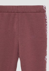 Bordeaux leggings van gemêleerd stof, met een gladde tailleband en witte bedrukte letters aan de zijkant.