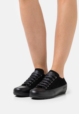 Černé tenisky kombinující semišovou a koženou část, zaoblenou špičku, plochou černou gumovou podrážku a kovové průvleky na tkaničky.