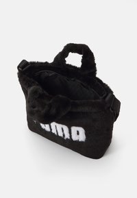 Sort faux fur taske med en blød tekstur, der har korte håndtag og lynlåslukning. Bemærkelsesværdig hvid logo-detalje på fronten.