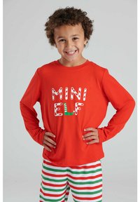 Camisa de manga larga roja con estampado blanco y verde de "MINI ELF", combinada con pantalones a rayas verdes y blancos con acentos rojos.