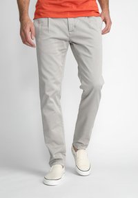 Lichtgrijze chino's met frontpleats, slim fit, gemaakt van gladde stof, gecombineerd met witte instapschoenen en een casual oranje t-shirt.