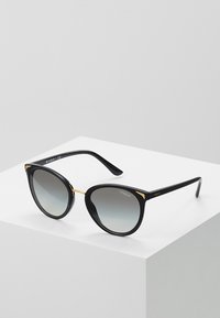Black sunglasses with cat-eye shape, gradient gray lenses, gold accents at the corners, and glossy plastic frames.