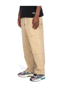 Beige bredde ben denimbukser med synlige stikninger og sidelommer, parret med farverige sportsko med mesh og gummi detaljer.