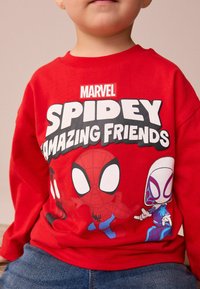 Czerwona koszula z długim rękawem z grafiką postaci Spider-Mana oraz napisem „MARVEL SPIDEY AMAZING FRIENDS” drukowanym na czarno-biało.