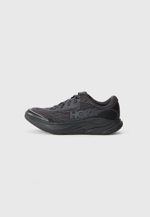 Chaussure de sport noire avec un dessus en maille texturée, semelle rembourrée surélevée et capuchon renforcé. Présente un logo sur le côté. Design léger.
