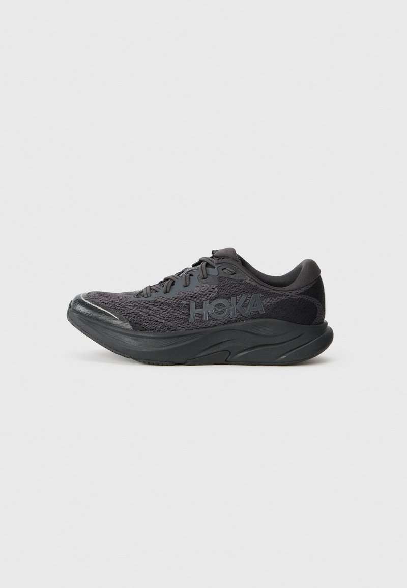 Chaussure de sport noire avec un dessus en maille texturée, semelle rembourrée surélevée et capuchon renforcé. Présente un logo sur le côté. Design léger.