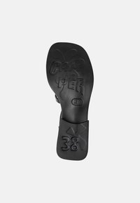 Black rubber shoe sole with raised "CAM PER" lettering, size "38," and a decorative pattern; flat, smooth texture, minimal detailing.