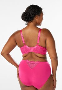 Švītra spilgti rozā apakšveļas komplekts ar mežģīņu apdari krūšturī ar regulējamām lencītēm un saskaņotu augsta vidukļa biksīšu komplektu ar smalkām mežģīņu detaļām.