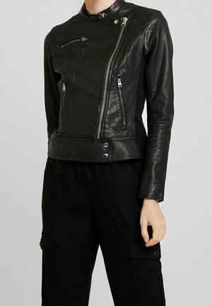 Veste de motard en cuir noir avec une fermeture éclair asymétrique, un col montant et plusieurs poches zippées. Design ajusté avec une texture lisse.