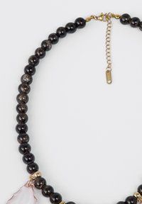 Collana di perle nere con pietre tonde lisce, pendente in geode rosa chiaro e chiusura ed elementi dorati. Catena regolabile inclusa.