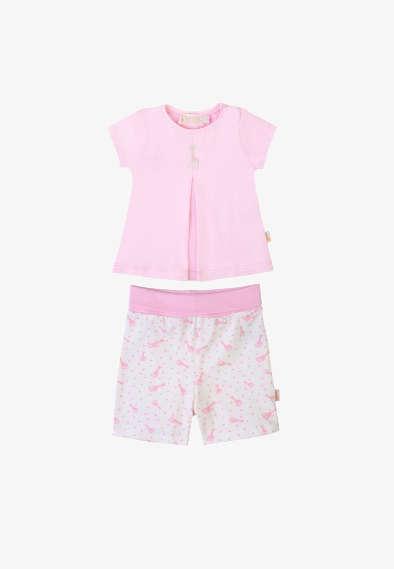 Top a maniche corte rosa chiaro con dettaglio di giraffa ricamato e una plissettatura. Pantaloni corti bianchi abbinati con motivo di giraffe rosa e pois.