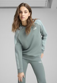 Completo felpa e leggings verde chiaro con accenti bianchi e logo Puma. Realizzato in materiale morbido, presenta maniche lunghe e scollatura a girocollo.