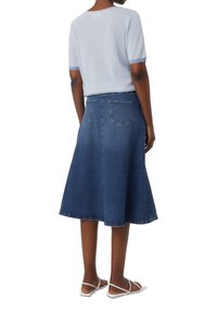 Jeans A-Linien-Rock mit mittellangem Schnitt, versehen mit leichter Ausbleichung und Gesäßtaschen, kombiniert mit einem gestreiften Strickoberteil in Blau und Weiß.