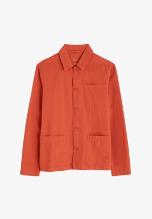 Camisa de hombre en tejido color óxido naranja, con cuello italiano, cierre de botones, un bolsillo en el pecho y dos bolsillos de parche en la parte frontal.