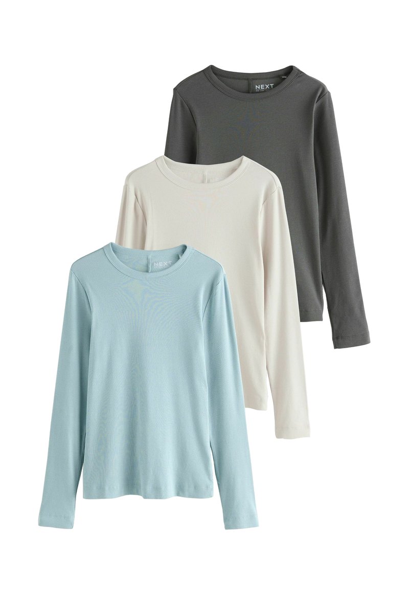 Trois t-shirts à manches longues en bleu clair, beige et gris foncé. Texture côtelée et encolures rondes. Étiquette de marque visible sur le t-shirt foncé.