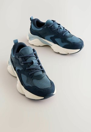Blå sneakers med mesh- og ruskindmateriale, rund tå, tyk hvid sål, tonale snørebånd og en fremhævet hællap.